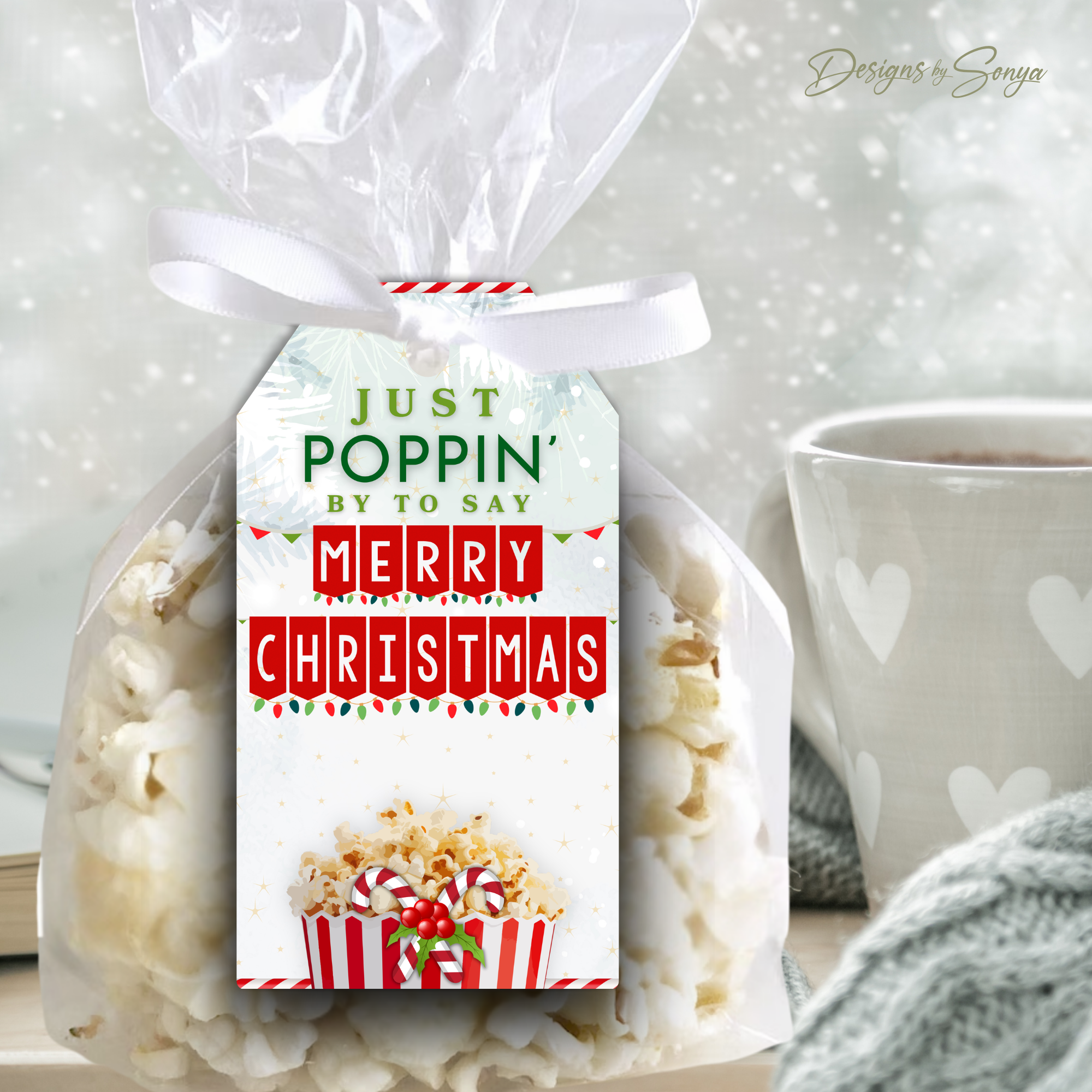 White & Red Christmas Popcorn Tag Close-Up – Festive “Just Poppin’ By to Say Merry Christmas” gift tag with candy cane popcorn graphic attached to a bag of popcorn beside a mug.