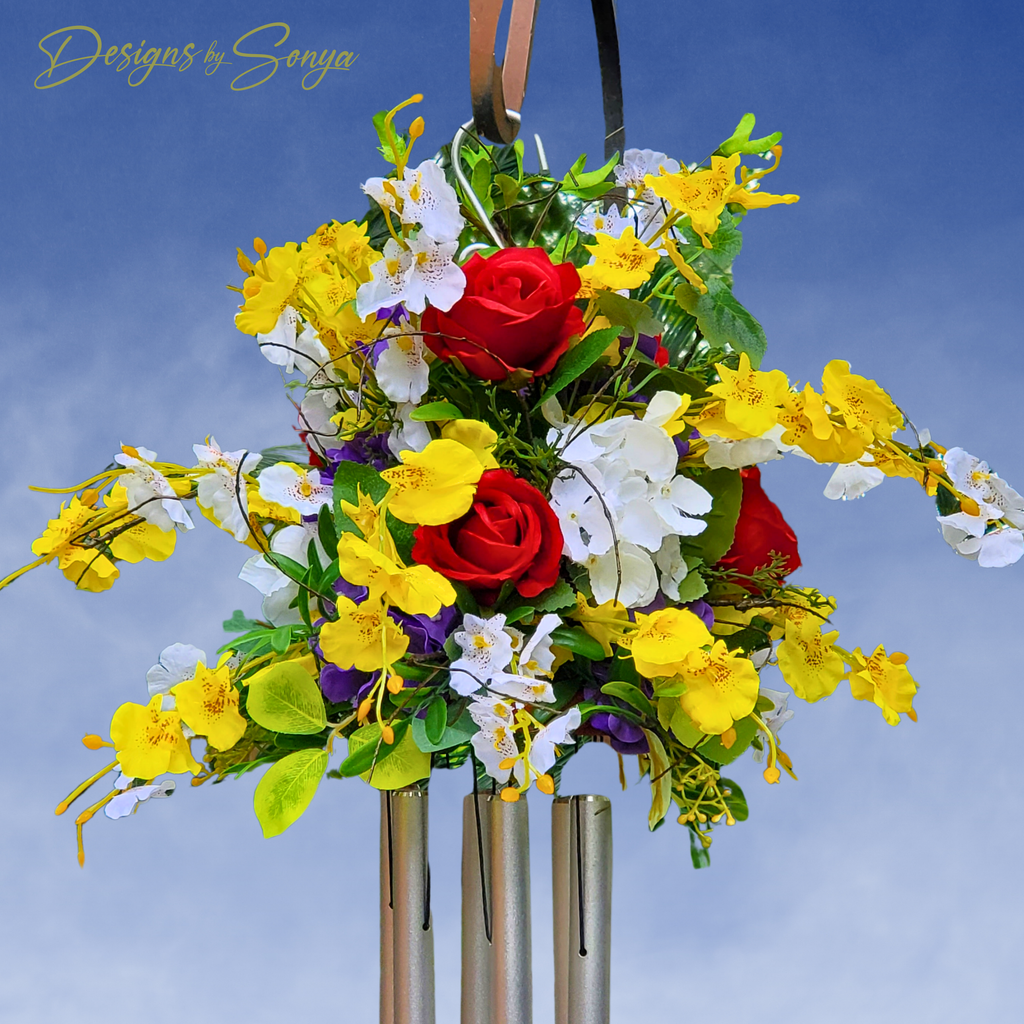 Floral Wind Chime Arrangement
Handmade wind chime adorned with red roses, yellow orchids, and white blossoms, designed as a memorial or garden tribute.