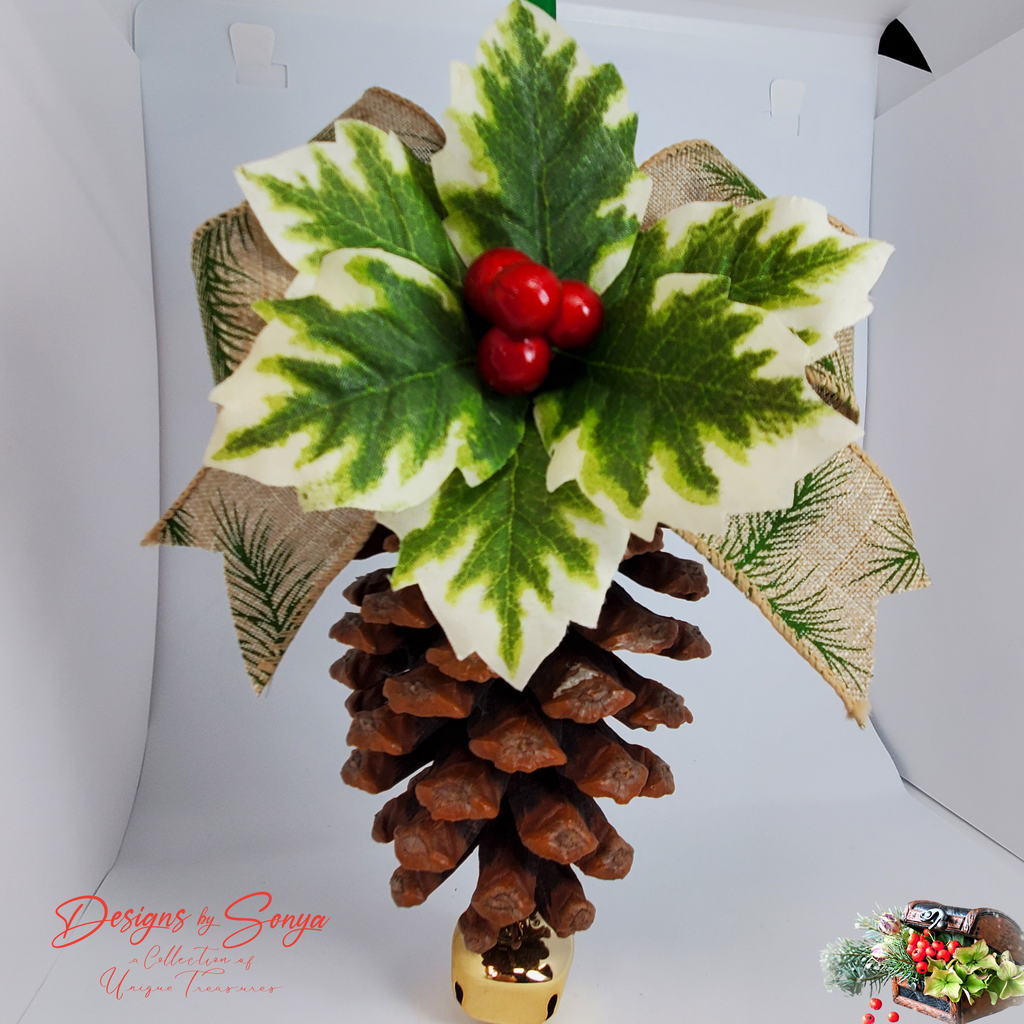 Studio Front View with Burlap Ribbon
Front studio view of a handmade pinecone ornament featuring faux holly leaves, glossy red berries, burlap ribbon with pine print, green satin hanger and gold bell; rustic Christmas decoration.