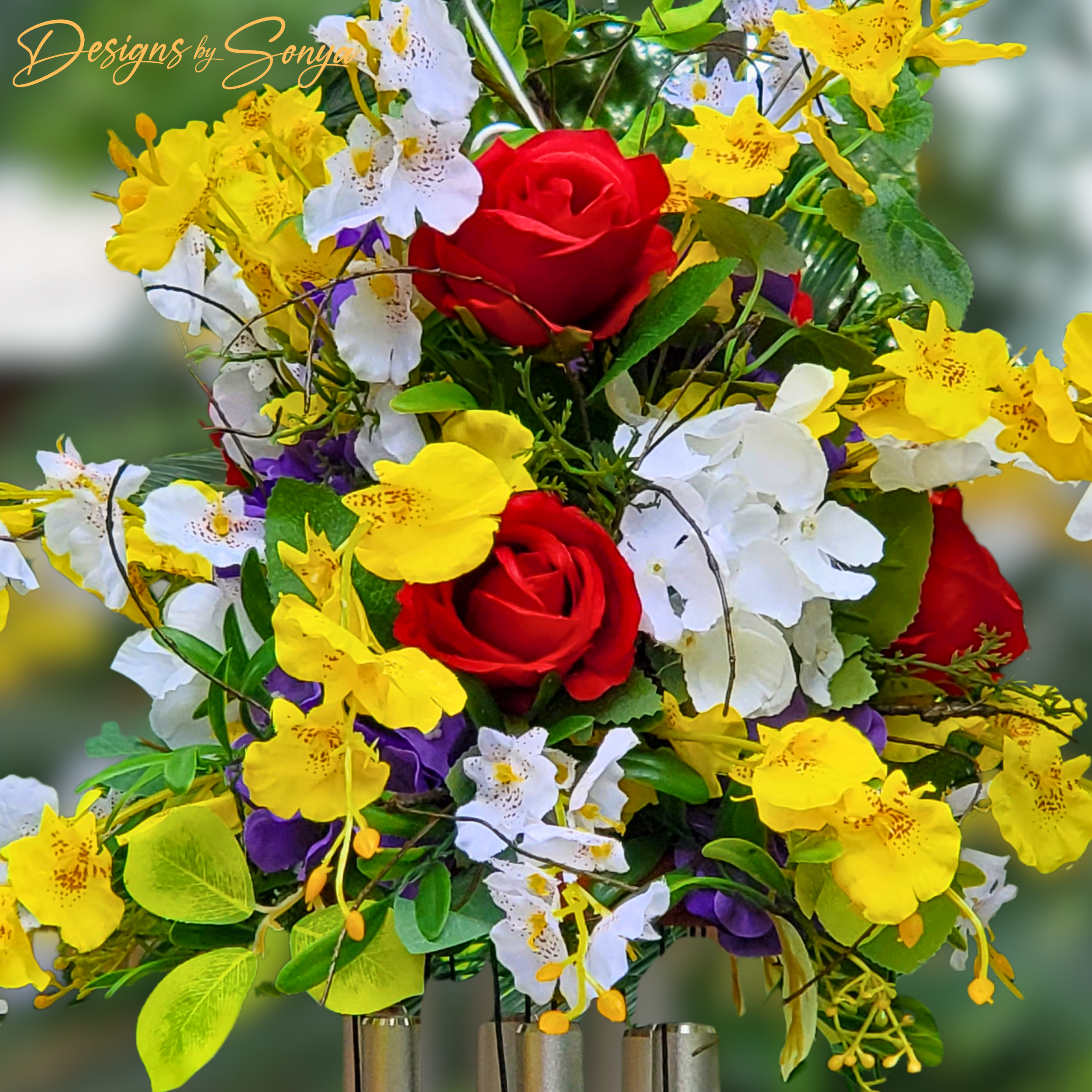 Close-Up of Flowers
Detailed view of lifelike red roses, golden orchids, and white florals with greenery in a handcrafted memorial wind chime arrangement.