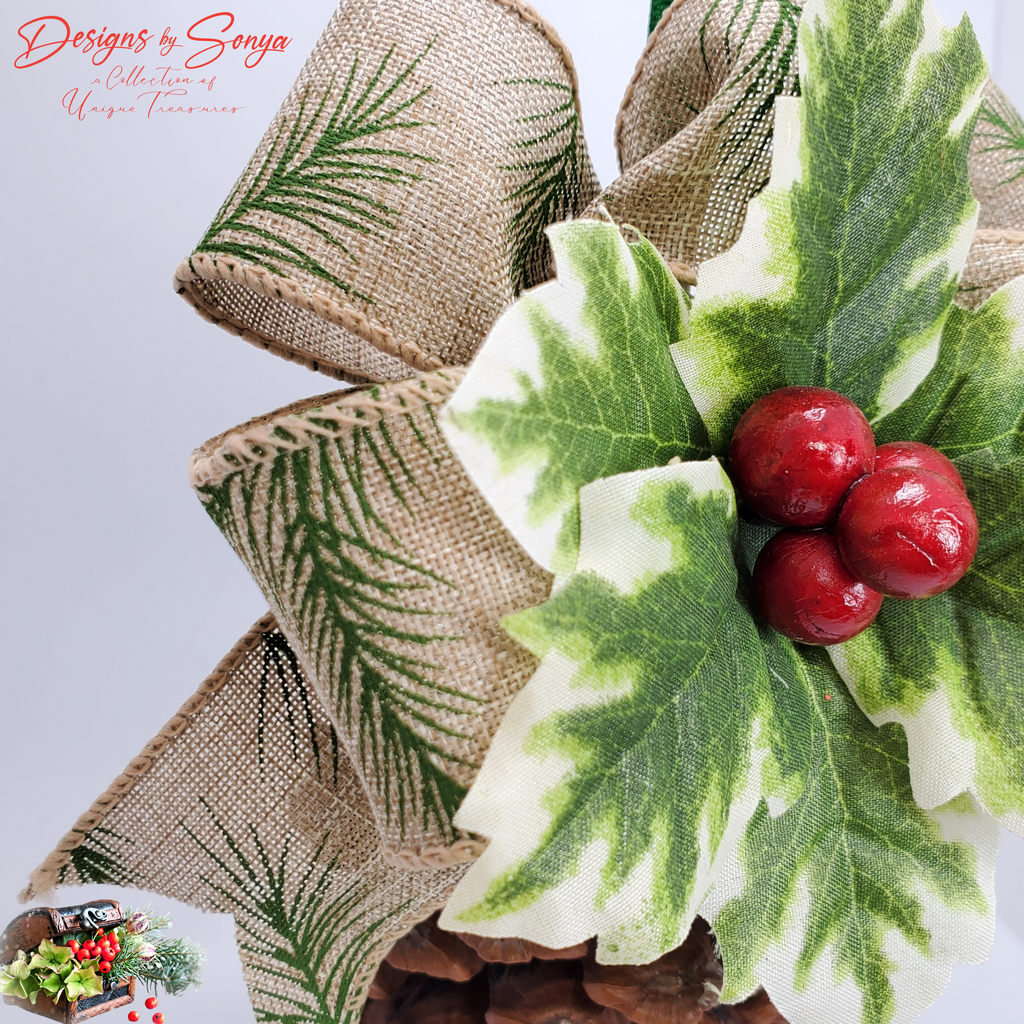 Burlap Ribbon with Pine Print Detail
Detailed view of wired burlap ribbon with green pine needle print and stitched edges layered behind the holly on the pinecone ornament; farmhouse holiday style.