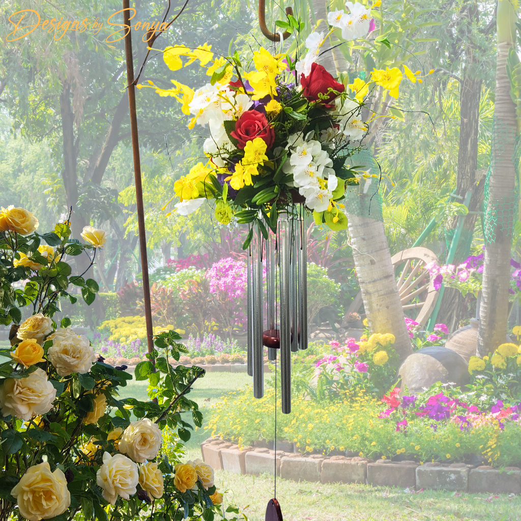 Garden Display with Roses
Handmade floral wind chime with red roses and orchids showcased in a vibrant garden setting.